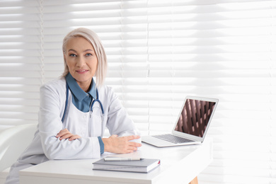 Portrait of mature female doctor in white coat at workplace