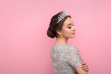 Photo of Beautiful young woman wearing luxurious tiara on pink background, space for text