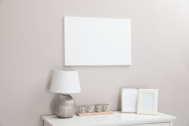 Photo of Blank canvas on wall over console table with decor indoors. Space for design