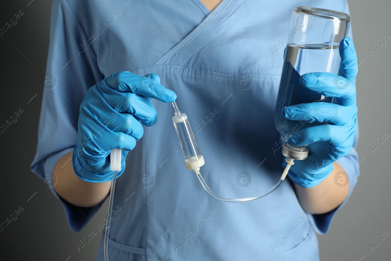 Photo of Nurse with IV infusion set on grey background, closeup