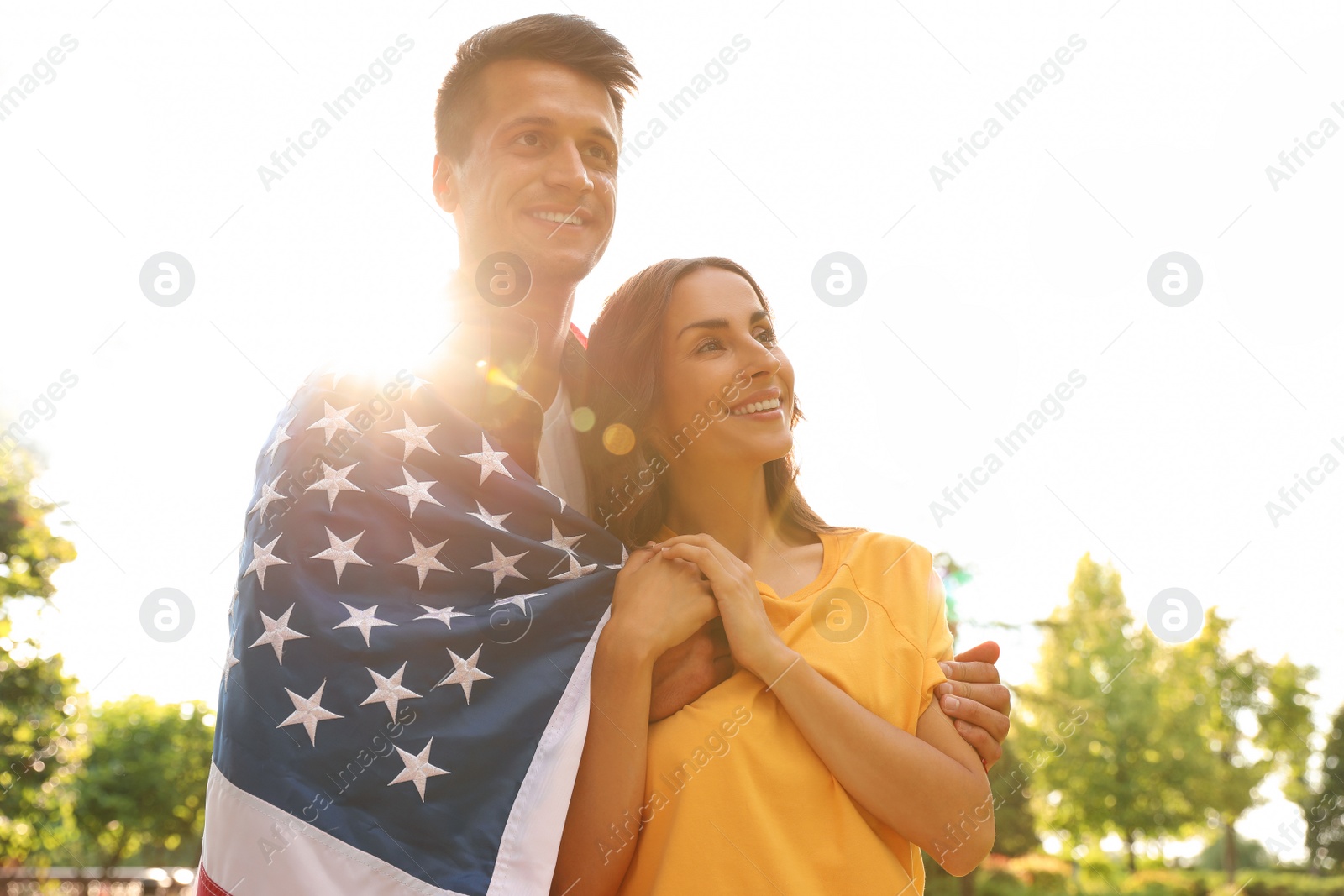 Photo of Man in military uniform with American flag and his wife at sunny park