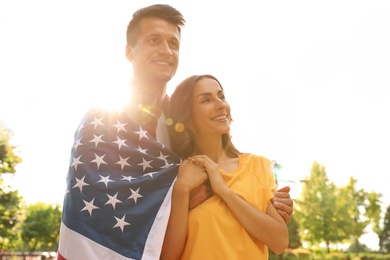 Man in military uniform with American flag and his wife at sunny park