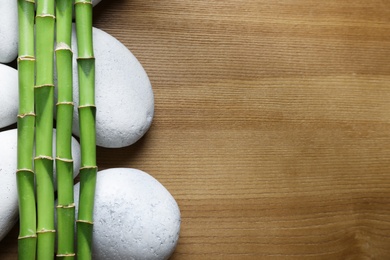 Photo of Flat lay composition with green bamboo stems on wooden background. Space for text