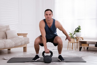 Muscular man training with kettlebell at home