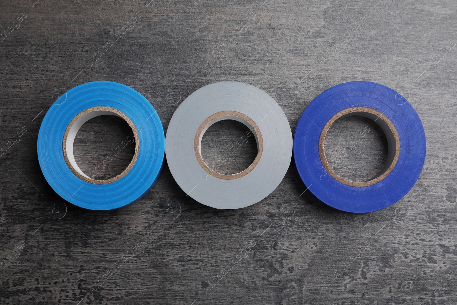 Photo of Colorful insulating tapes on dark gray background, top view