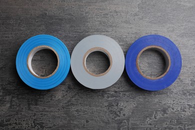 Photo of Colorful insulating tapes on dark gray background, top view