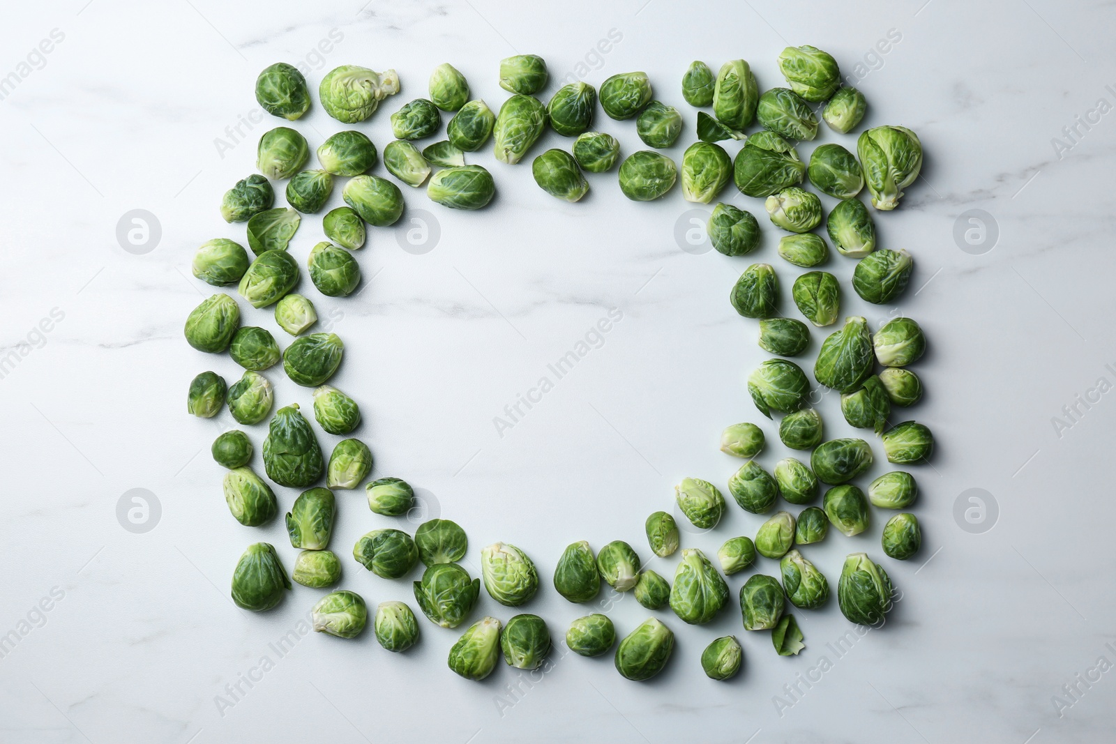 Photo of Frame of Brussels sprouts on white marble table, flat lay. Space for text