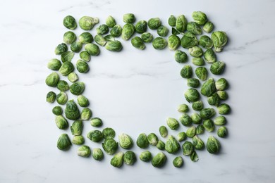 Frame of Brussels sprouts on white marble table, flat lay. Space for text