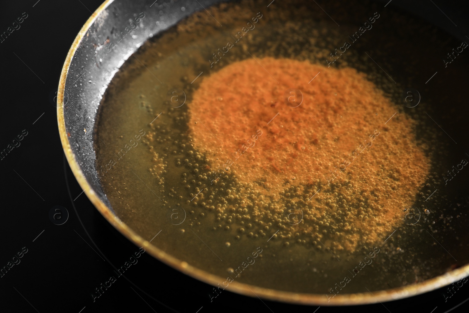 Photo of Frying pan with used cooking oil on stove, closeup