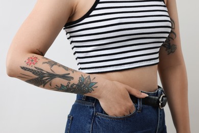 Woman with cool tattoos on gray background, closeup
