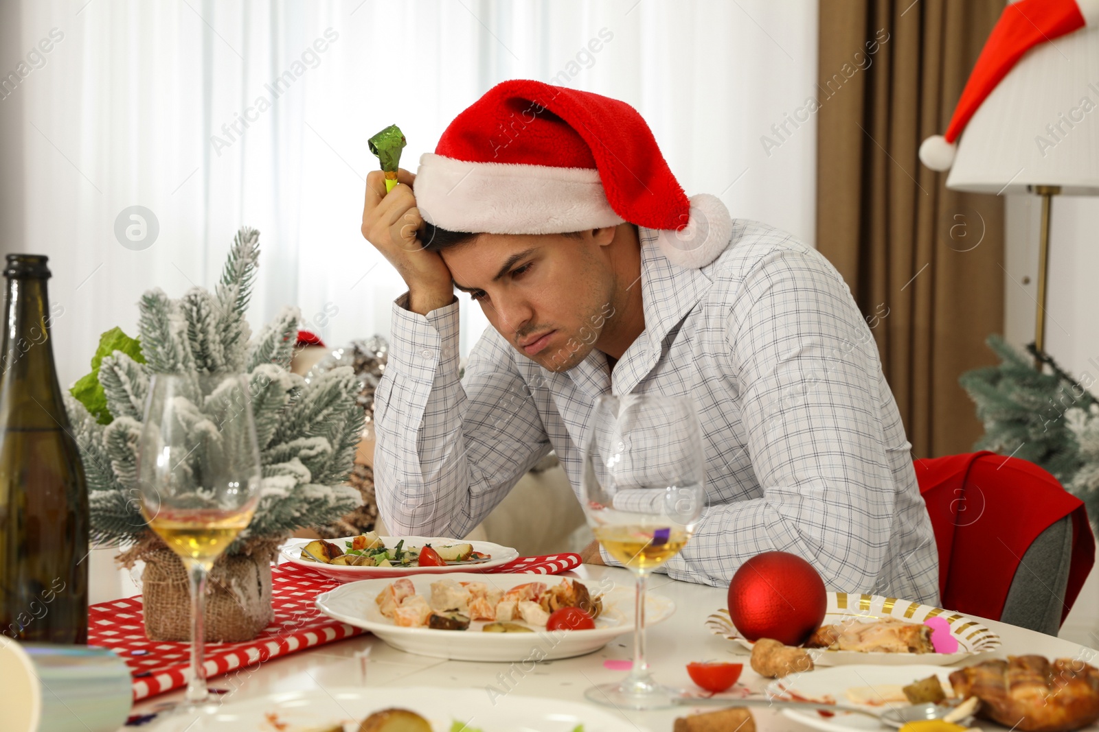 Photo of Man suffering from hangover at table after New Year party