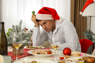 Man suffering from hangover at table after New Year party