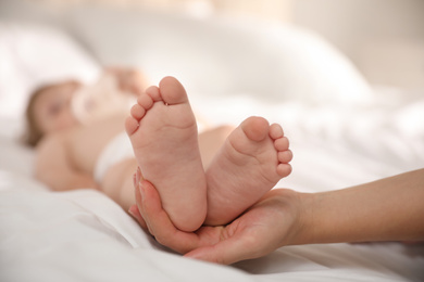 Photo of Orthopedist examining little baby on bed, closeup