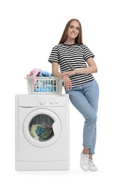 Beautiful young woman with laundry basket near washing machine on white background