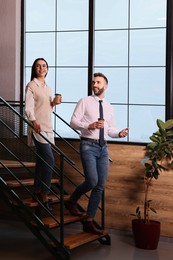 Photo of Coworkers talking during coffee break on stairs in office