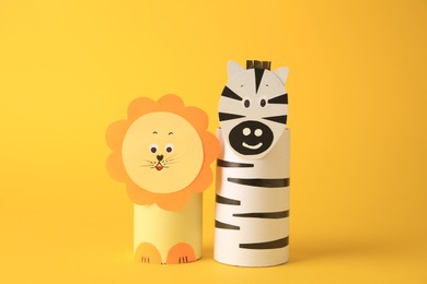 Photo of Toy lion and zebra made from toilet paper hubs on yellow background. Children's handmade ideas
