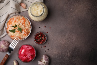 Photo of Delicious sauerkraut prepared according to different recipes and spices on brown table, flat lay. Space for text