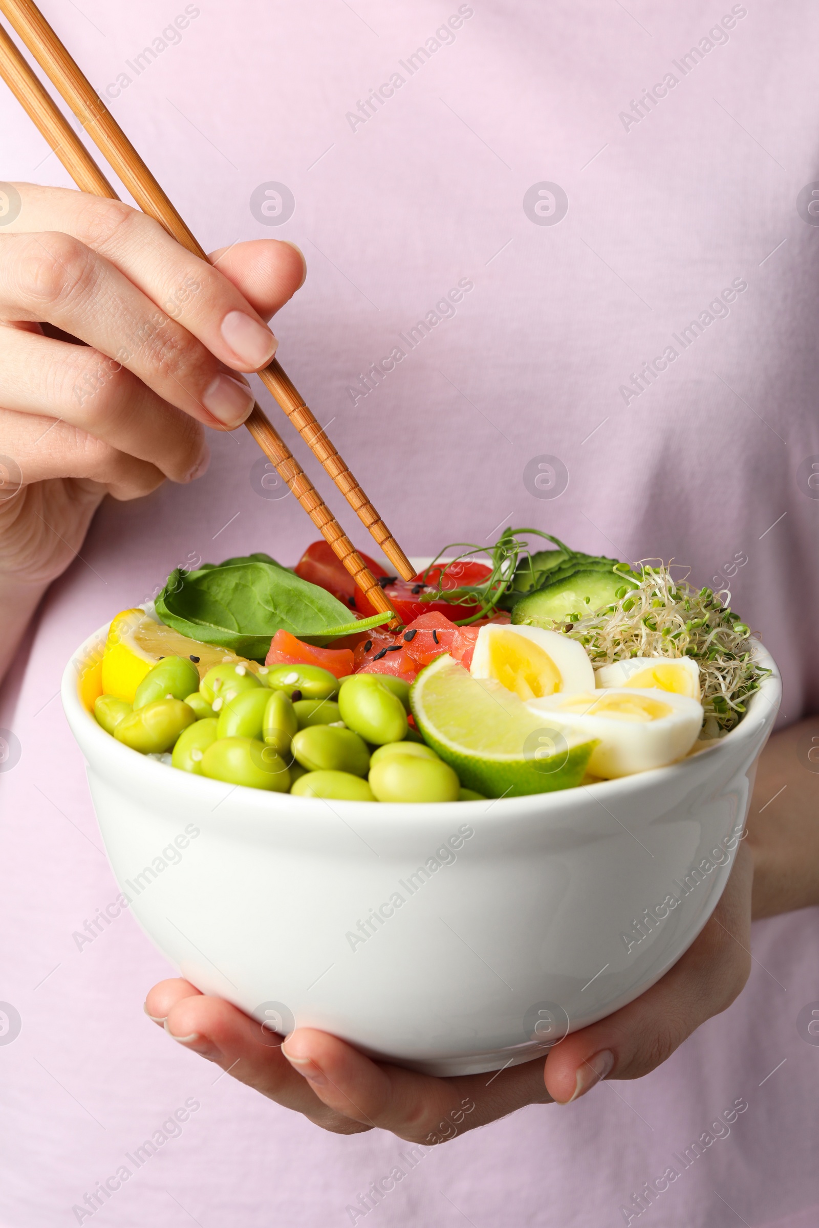 Photo of Woman holding delicious poke bowl quail eggs, fish and edamame beans, closeup