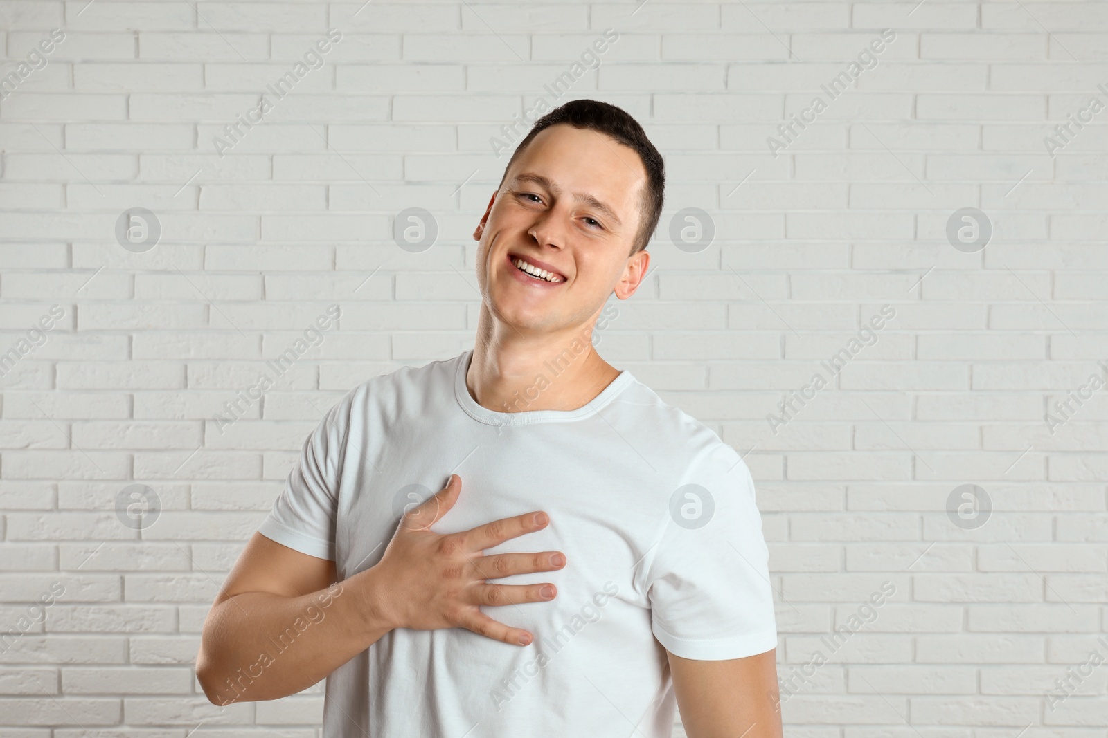 Photo of Handsome young man near white brick wall