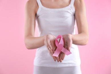 Young woman with pink ribbon on color background. Gynecology