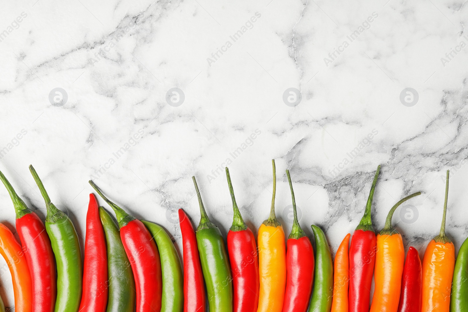 Photo of Different ripe chili peppers on marble table, flat lay. Space for text