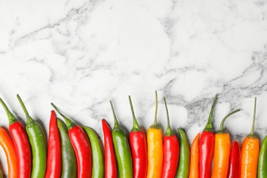 Photo of Different ripe chili peppers on marble table, flat lay. Space for text