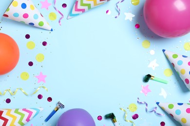 Photo of Frame made of party hats and birthday decor on light blue background, flat lay. Space for text.