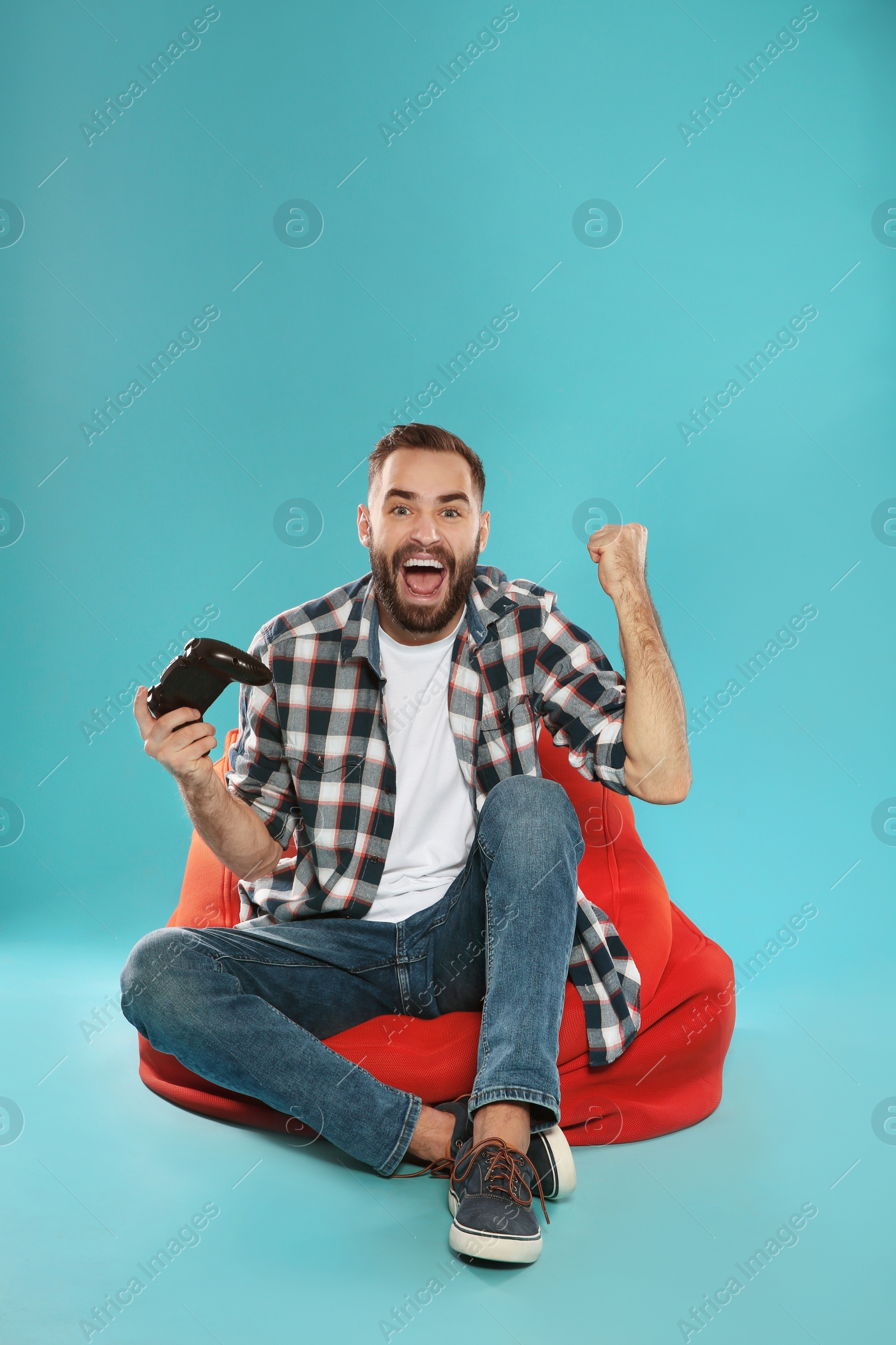 Photo of Emotional young man playing video games with controller on color background. Space for text