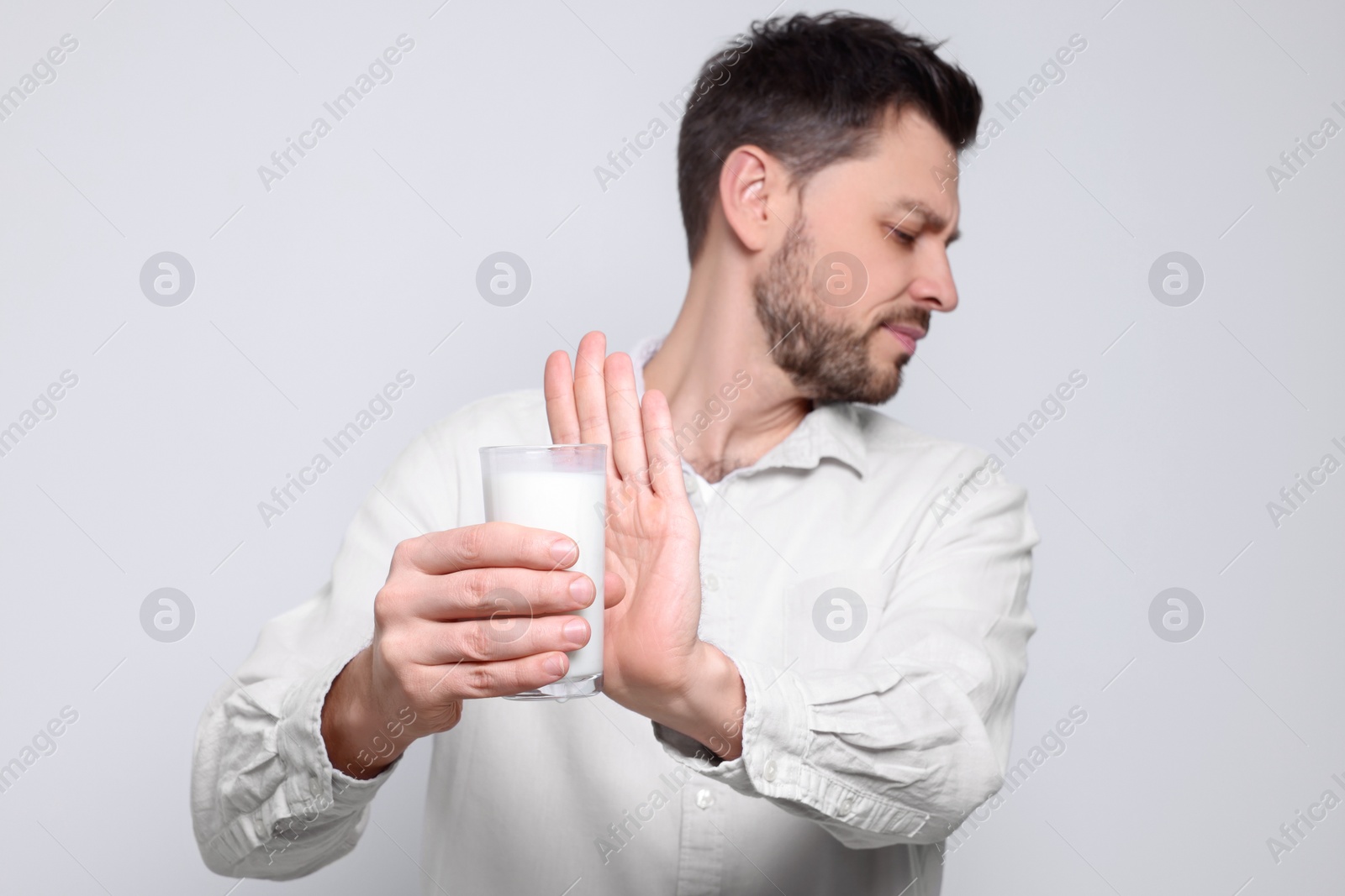 Photo of Man with glass of milk suffering from lactose intolerance on white background