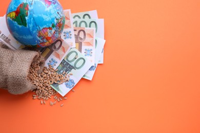 Photo of Import and export concept. Globe, bag of wheat grains and banknotes on orange background, above view. Space for text