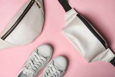 Flat lay composition of stylish shoes and bum bags on color background