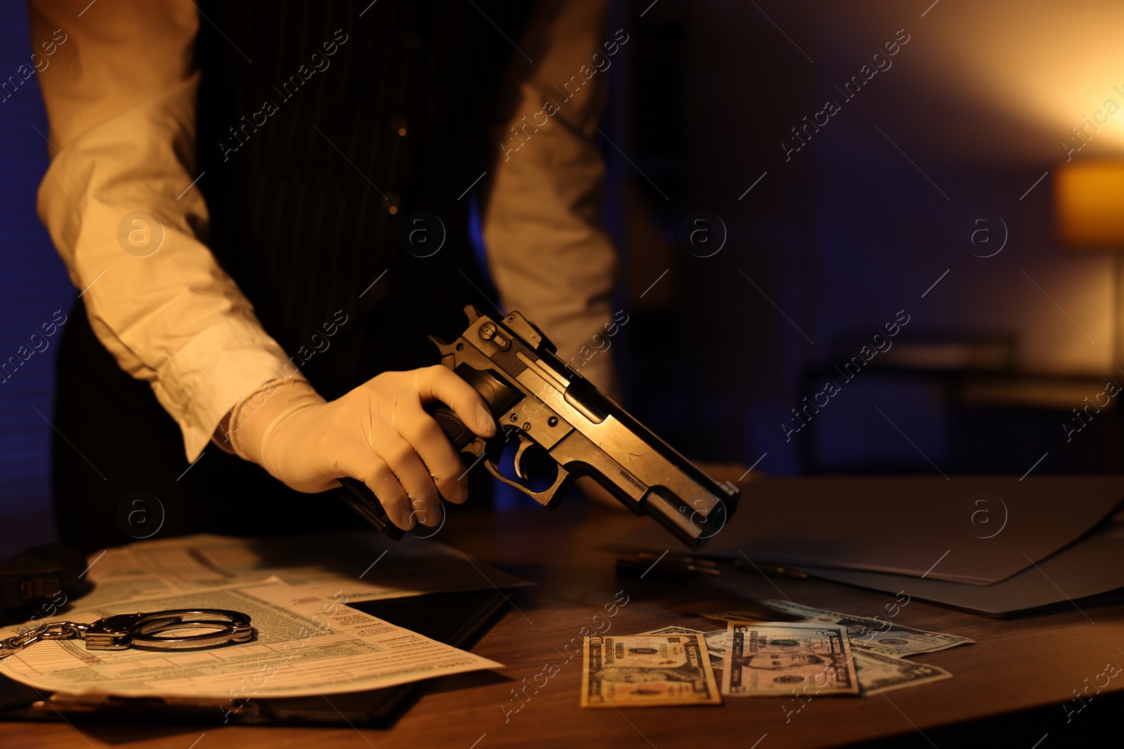 Photo of Professional detective in protective gloves working with evidence indoors at night, closeup