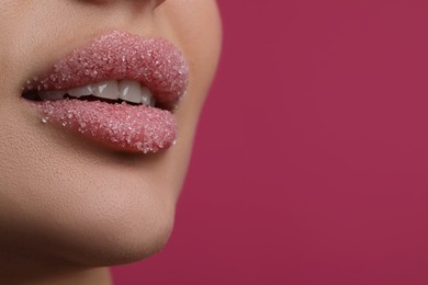 Photo of Young woman with beautiful lips covered in sugar, on pink background, closeup. Space for text