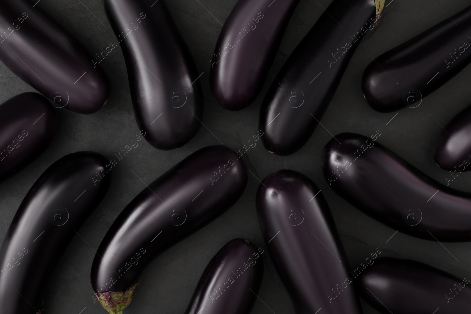 Photo of Raw ripe eggplants on black table, flat lay