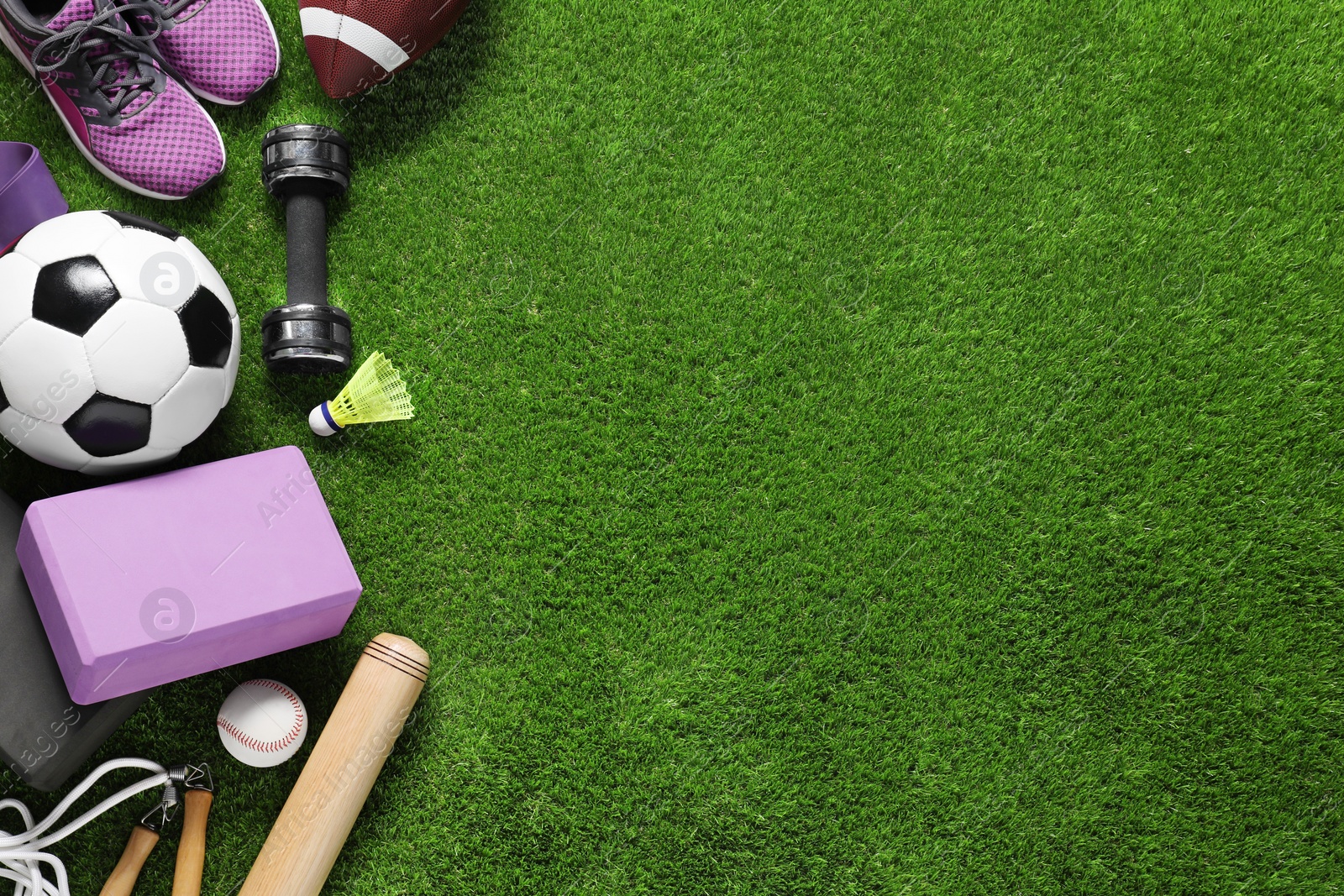 Photo of Different sport tools on green grass, flat lay. Space for text