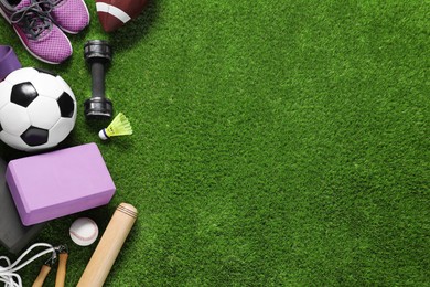 Photo of Different sport tools on green grass, flat lay. Space for text