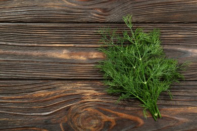 Fresh green dill with water drops on wooden table, top view. Space for text
