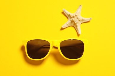 Photo of Sunglasses and starfish on color background, top view. Beach accessories