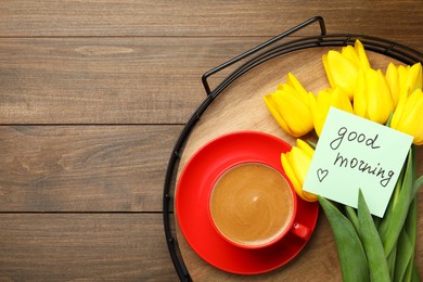 Photo of Tray with beautiful yellow tulips, cup of aromatic coffee and Good Morning note on wooden table, top view. Space for text