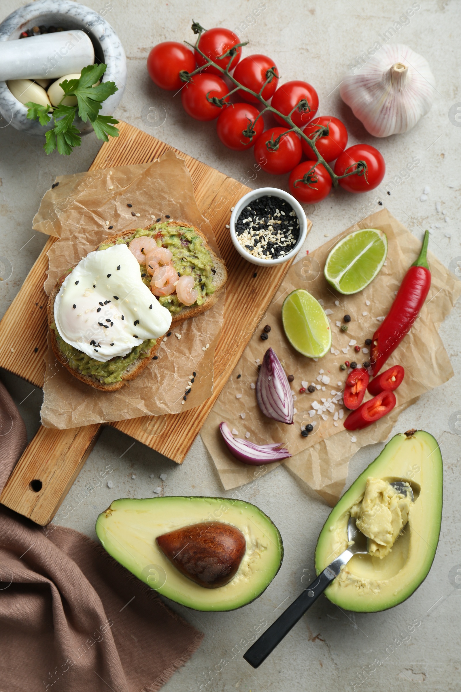 Photo of Delicious sandwich with guacamole, shrimps, fried egg and ingredients on light grey table, flat lay