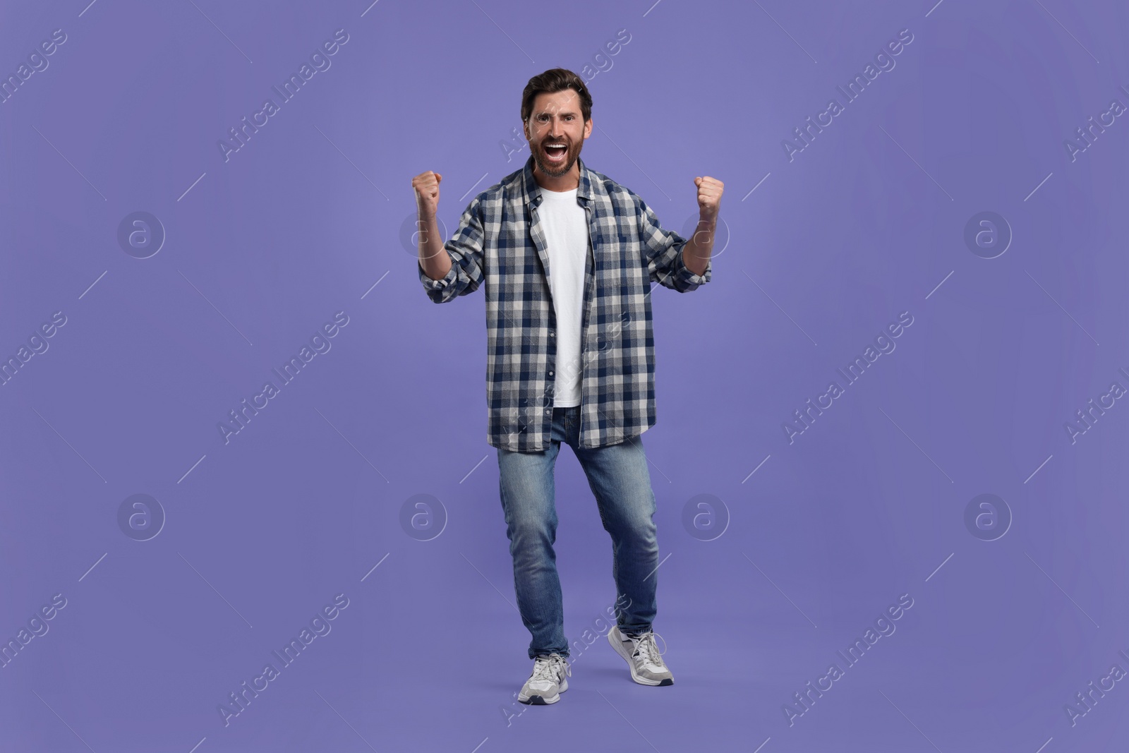 Photo of Emotional sports fan celebrating on purple background