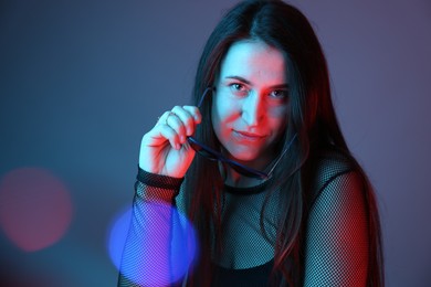 Photo of Portrait of beautiful young woman with sunglasses on color background