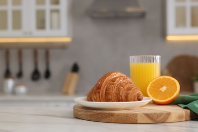 Breakfast served in kitchen. Fresh croissant and orange juice on white table. Space for text