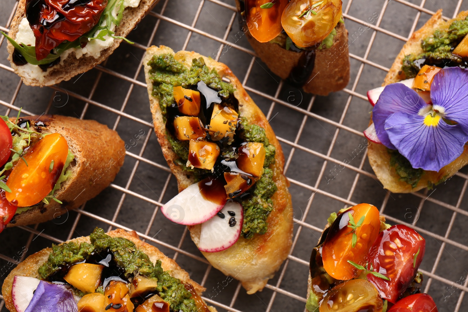 Photo of Delicious bruschettas with different toppings and balsamic vinegar on gray table, flat lay