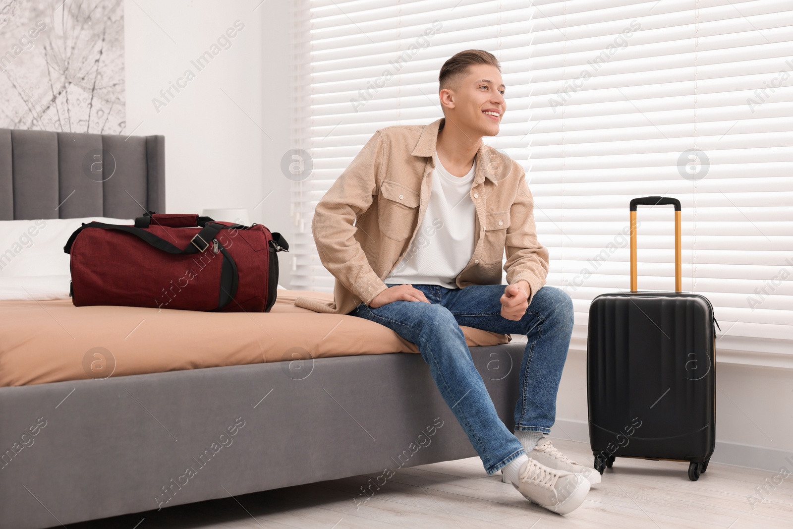 Photo of Smiling guest relaxing on bed in stylish hotel room