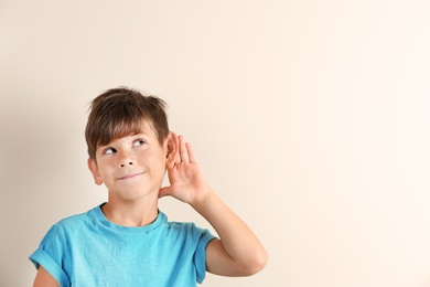 Photo of Cute little boy with hearing problem on light background. Space for text