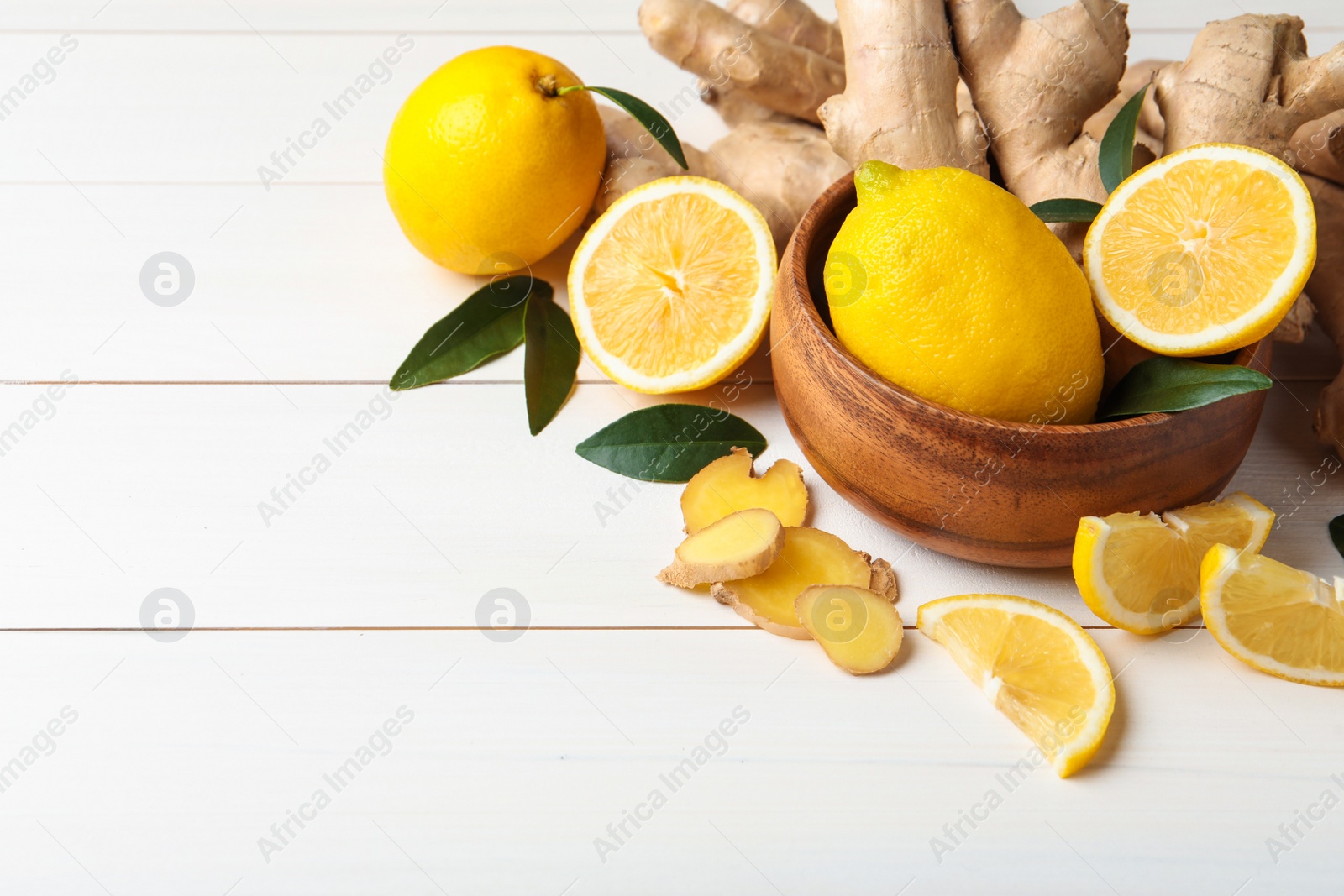 Photo of Fresh lemons and ginger on white wooden table. Space for text