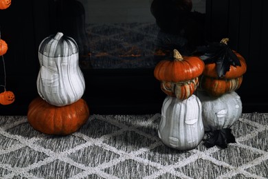 Colorful pumpkins on rug near fireplace. Halloween decorations
