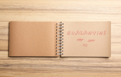Image of Open notebook on wooden table, top view. Counting days of quarantine during coronavirus outbreak 