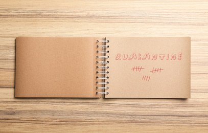 Open notebook on wooden table, top view. Counting days of quarantine during coronavirus outbreak 